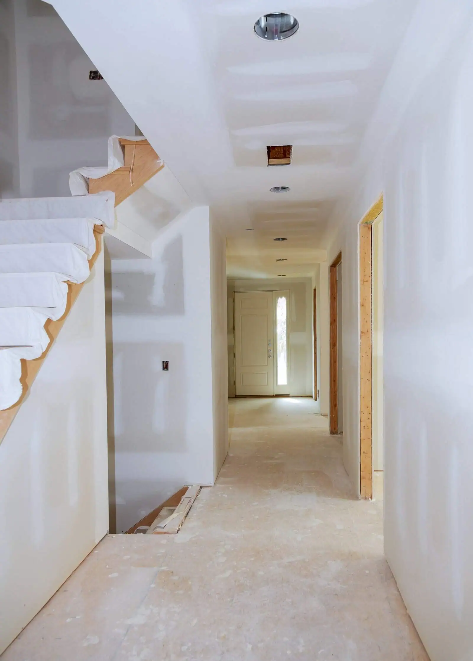 Interior hallway with drywall walls and ceiling, under construction, in a residential building.